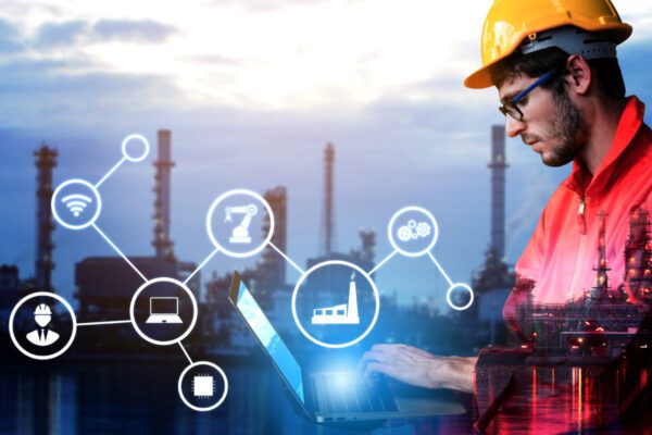 Industrial engineer wearing a hard hat, working on a laptop with digital icons.