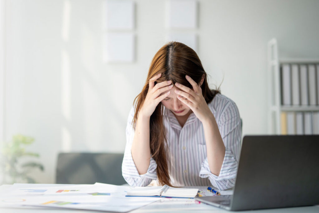 Stressed business professional reviewing reports at desk